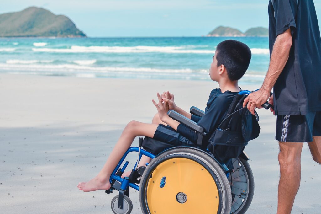 Happy disabled kid and parent in travel holidays concept, Blue Sea beach background.